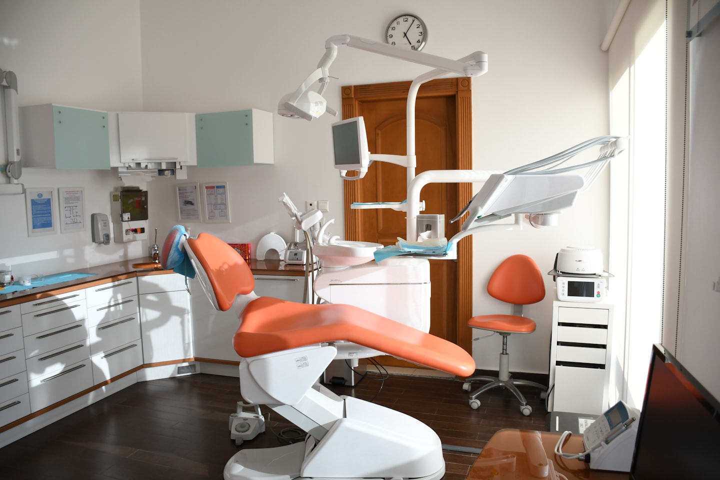 Moderna sala di esame dentistico con sedia arancione e attrezzature.