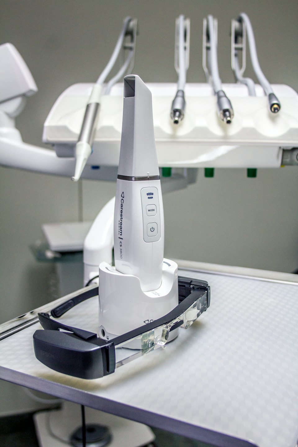 Scanner intraorale moderno e occhiali smart su un vassoio bianco.
