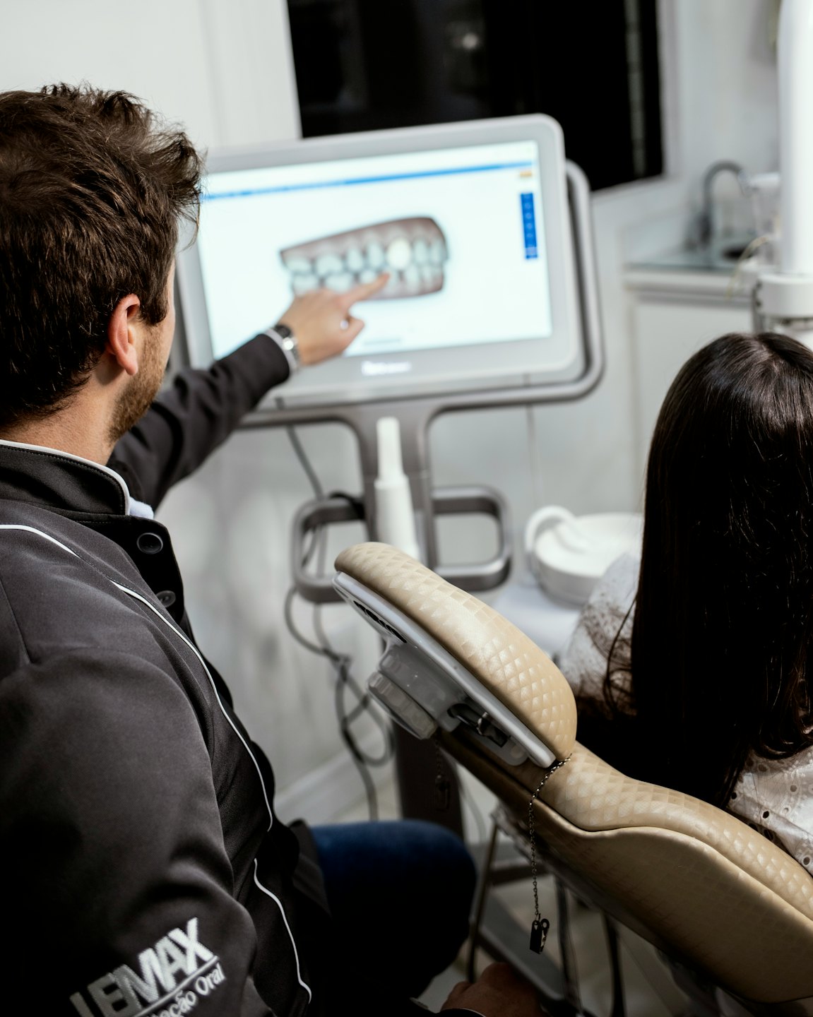 Dentista mostra un modello 3D di denti su uno schermo a un paziente.